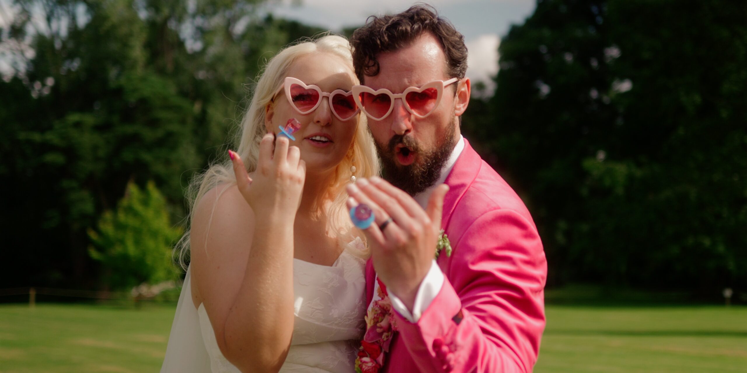 Bride and groom wearing matching pink heart sunglasses during their creative wedding at Montalto House